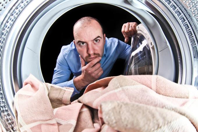 Človek skeptično pogleda v pralni stroj