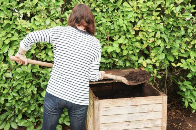 En kvinde vender kompost med en spade