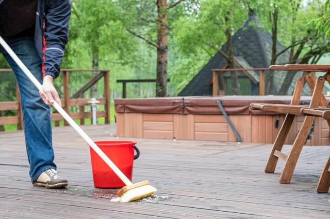 Pulisci la terrazza in legno con una miscela di scopa e detersivo