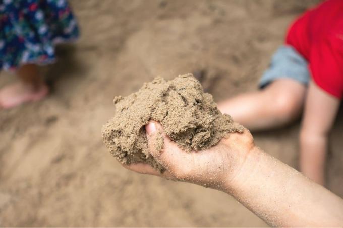 Lapsella on kourallinen hiekkaa hiekkalaatikossa