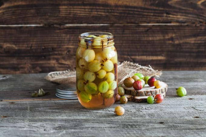 Gooseberries pickled in a jam jar on a wooden background