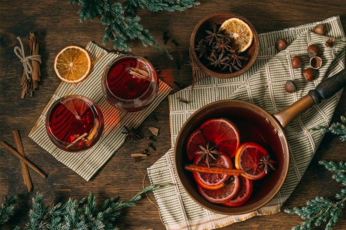 Mulled wine in a pot and glasses with cloves, cinnamon sticks and orange