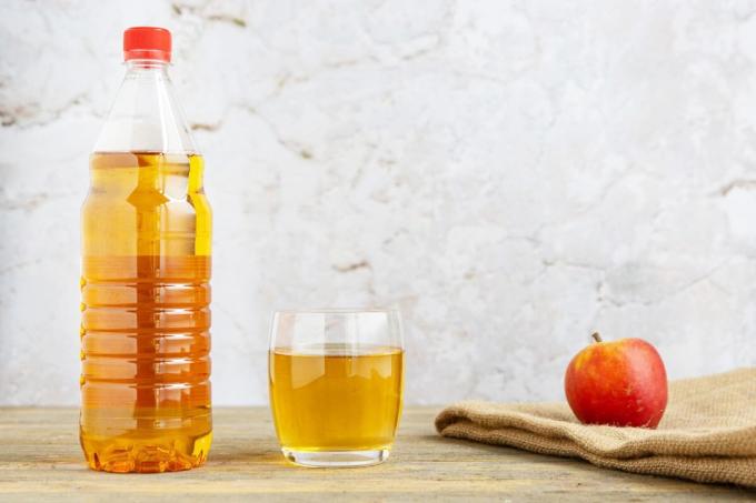 Apple cider vinegar with glass and apple on table