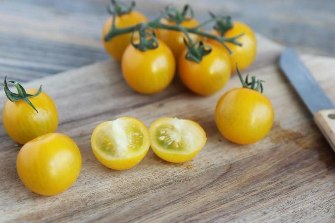 Ahşap kesme tahtası üzerinde dilimlenmiş sarı domates