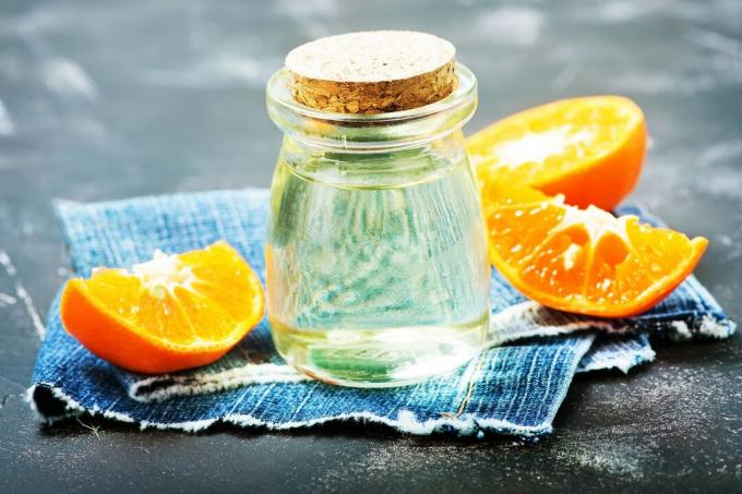 Fiolka olejku pomarańczowego na stole ze skórką pomarańczową