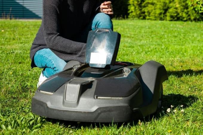 Žena kontroluje robot na trávniku