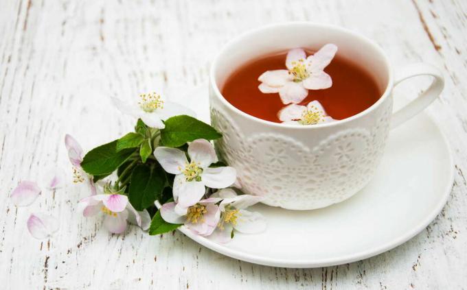 Apple blossoms in a tea and next to a tea
